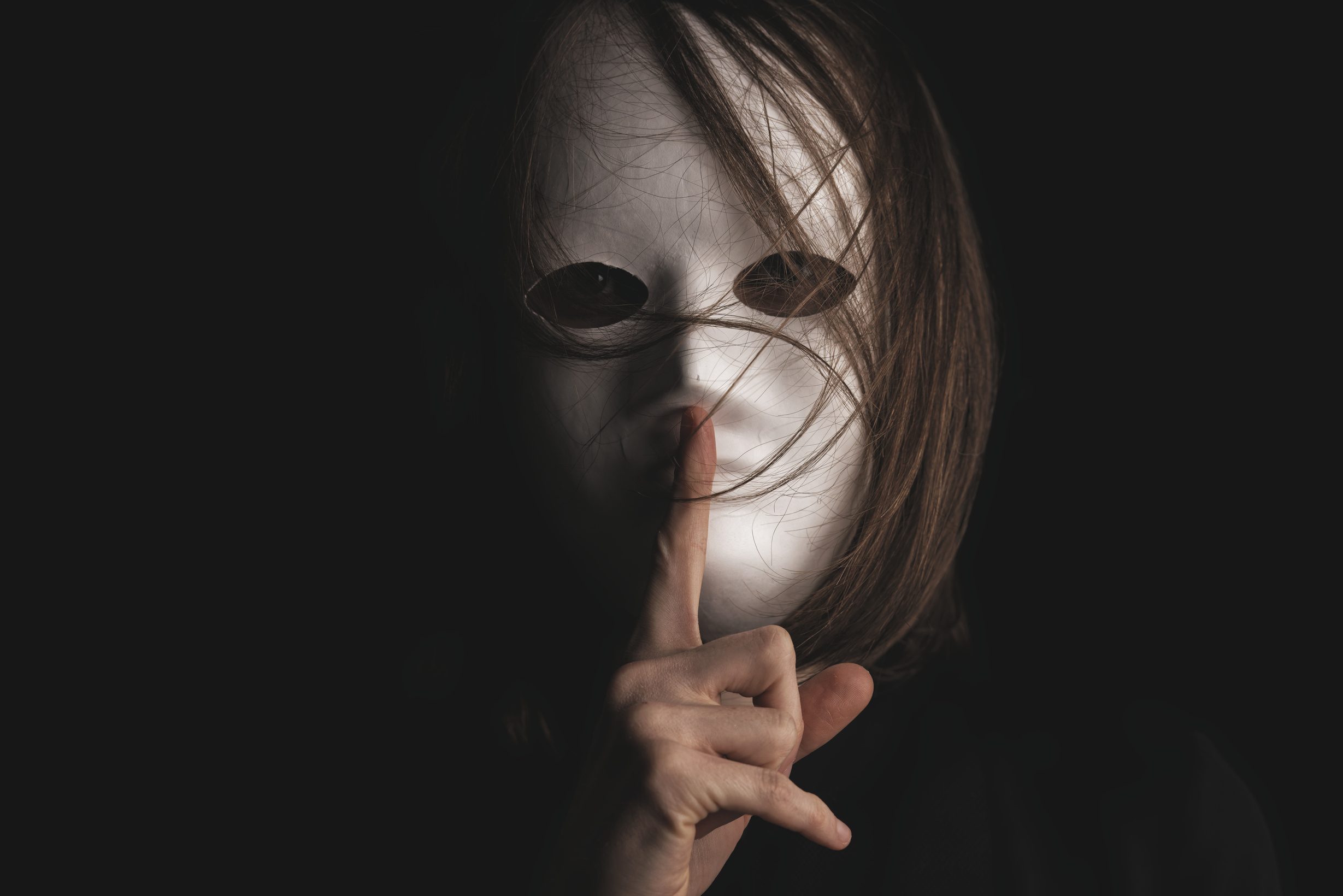 Person Covering Face with a White Mask with Silence Gesture